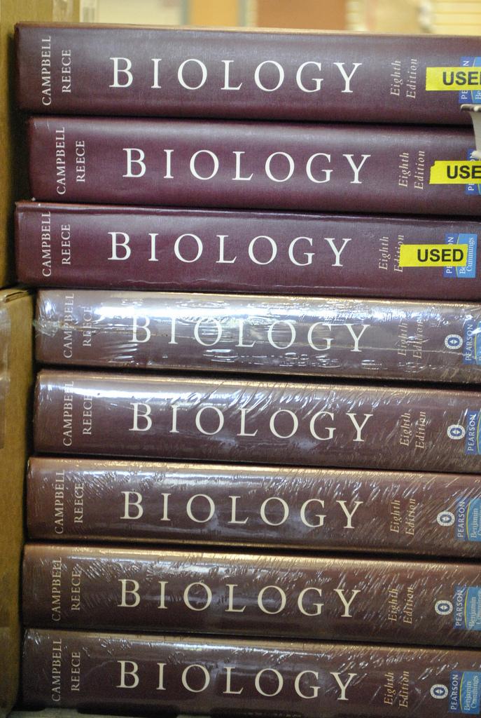 A stack of Biology textbooks from 2010, resting on a desk.