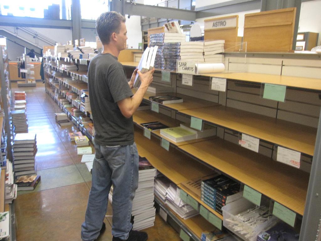 Baron Bredenberg, senior inventory and receiving clerk, stacks books for the upcoming semester, most of which will be available for rental. (Kevin Hayes/The Inquirer)