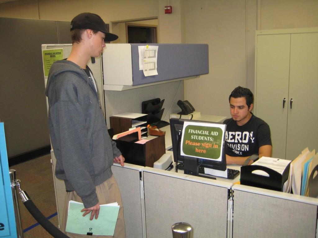 Student Kyle Mckeen-Reyes, left, waits as Federick Gil Mejia helps him in the Financial Aid office. Mckeen-Reyes is one of the 13,000 students receiving financial aid and must deal with the new appointment and assistance policy. (Alex Brendel)