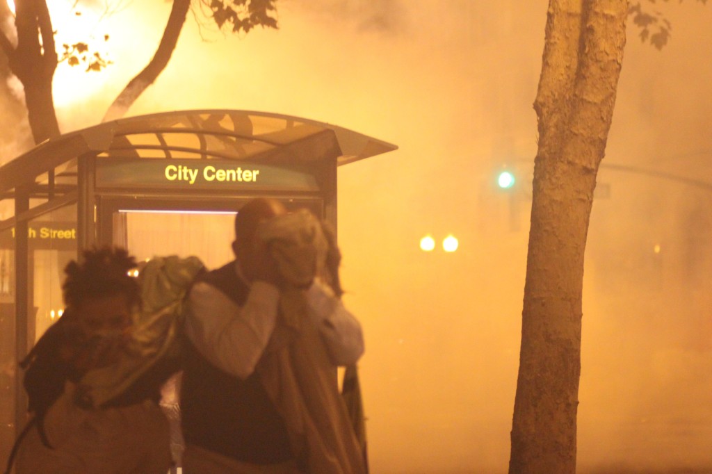 People cover their faces as they run away from the billowing tear gas unleashed by the police to disperse the protest outside Frank Ogawa Plaza Tuesday night. (Mike Alfieri/DVC Inquirer)