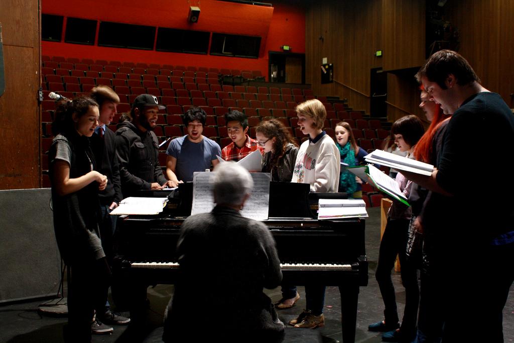 The cast of Spelling Bee gathers around the piano in the Performing Arts Center to practice their musical parts during rehearsal. 