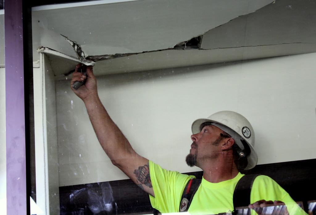 Flintco worker removes loose sheetrock before applying plywood to the damaged area.Photo credit: Hakeem Montes.