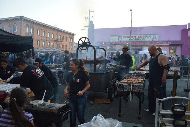 Man+grilling%2C+woman+selling%2C+crowd+buying.