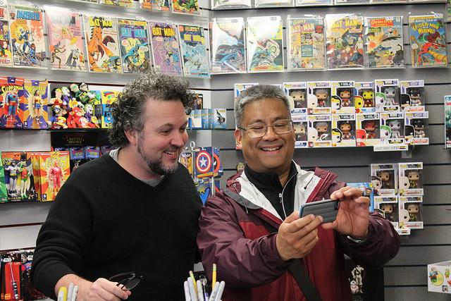 Comic book artist Darick Robertson poses for a selfie with a fan during a signing at Flying Colors Comic Book Store on November 19, 2016.