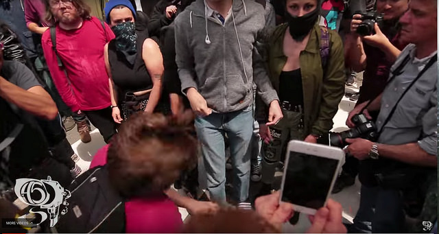 Screenshot of the protester in the pink shirt being struck with a bike lock during the Berkeley protests on April 15, 2017 