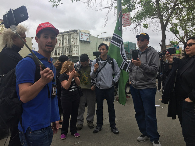 Rick Write (left), Kevin Chan (center) and various individuals live stream prior to the arraignment of Eric Clanton, outside of Wiley W. Manuel courthouse in Oakland on May 26