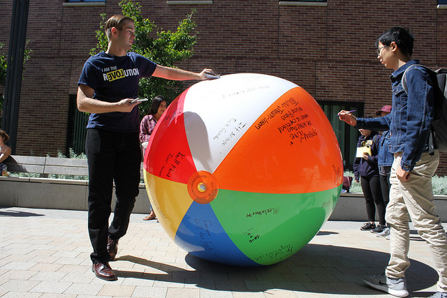A member of Young Americans for Liberty holds pamphlets advertising the organization while a student writes on the "Free Speech" ball in the Commons on Sept. 18, 2017. 